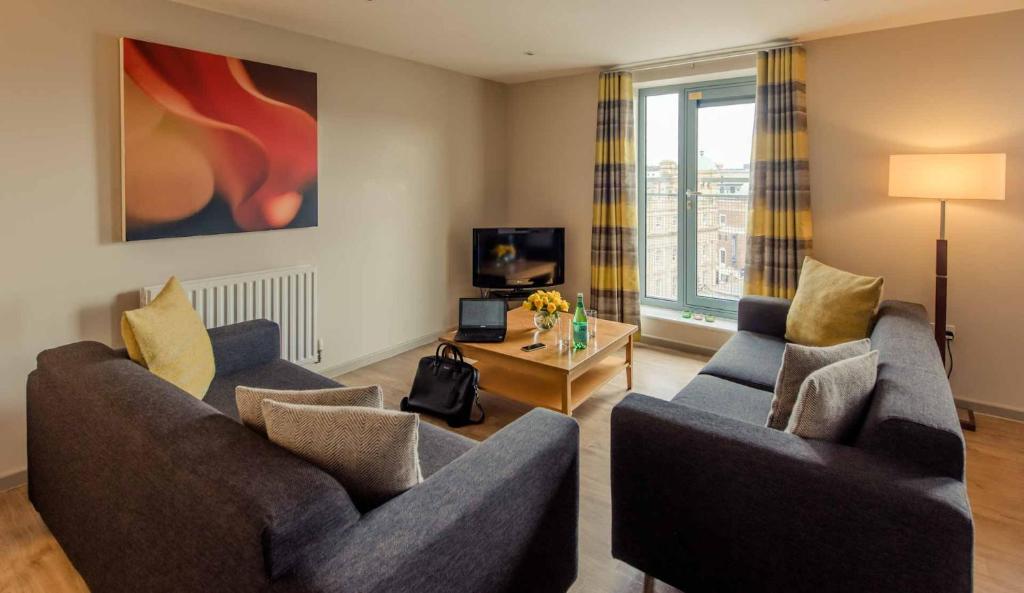 a living room with two couches and a table at PREMIER SUITES Newcastle in Newcastle upon Tyne