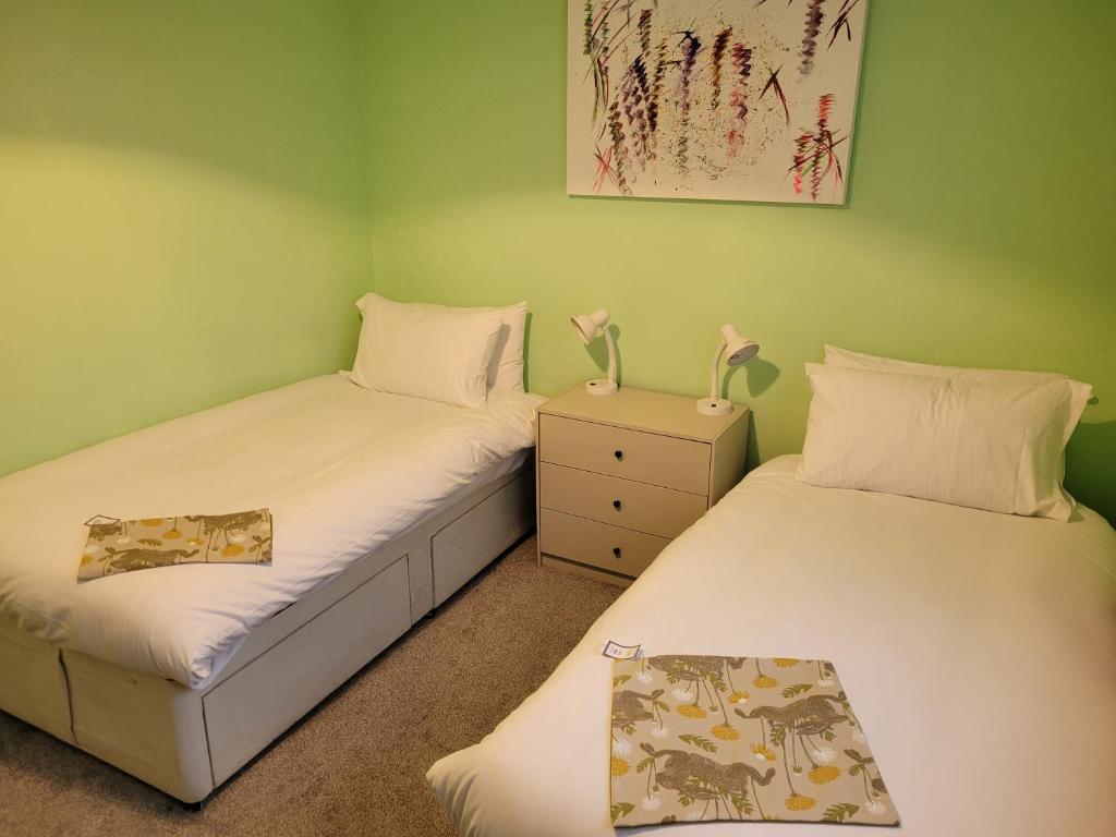 2 camas individuales en una habitación con paredes verdes en Rent Unique the Beeches 2bed, en Crawley
