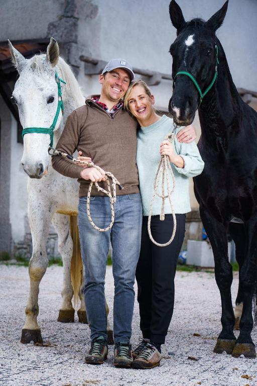 a man and a woman standing next to a black horse at Tmbin's barn - nature, horses, family in Sežana