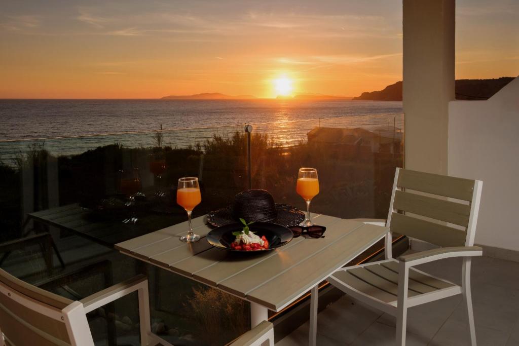 a table with a plate of food and two glasses of wine at Diamond Arillas Luxury Apartments in Arillas