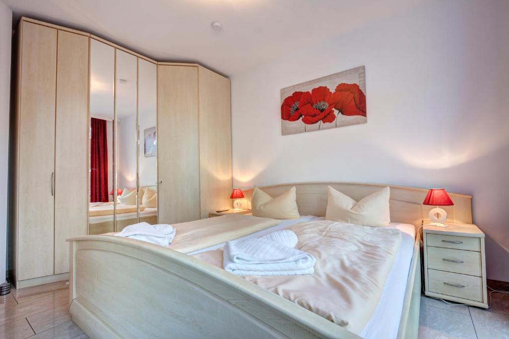 ein Schlafzimmer mit einem weißen Bett, einem Nachttisch und einem Spiegel in der Unterkunft Ostseeresidenz Gorki- Park - 11 mit Wellness und Schwimmbad in Bansin