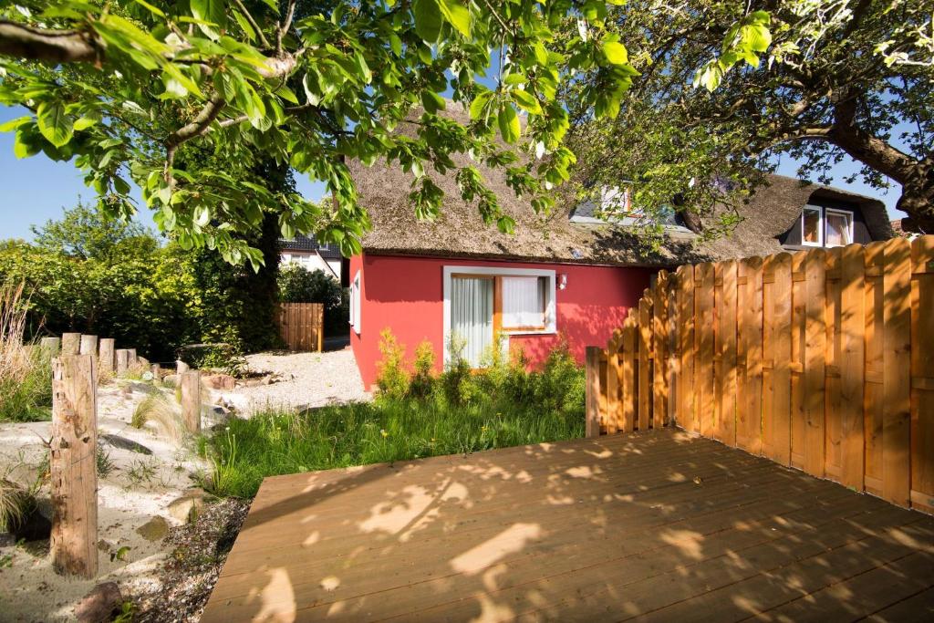 una casa roja con una valla de madera delante de ella en Ferienwohnung Meeresträume Wohnung 2, en Wustrow