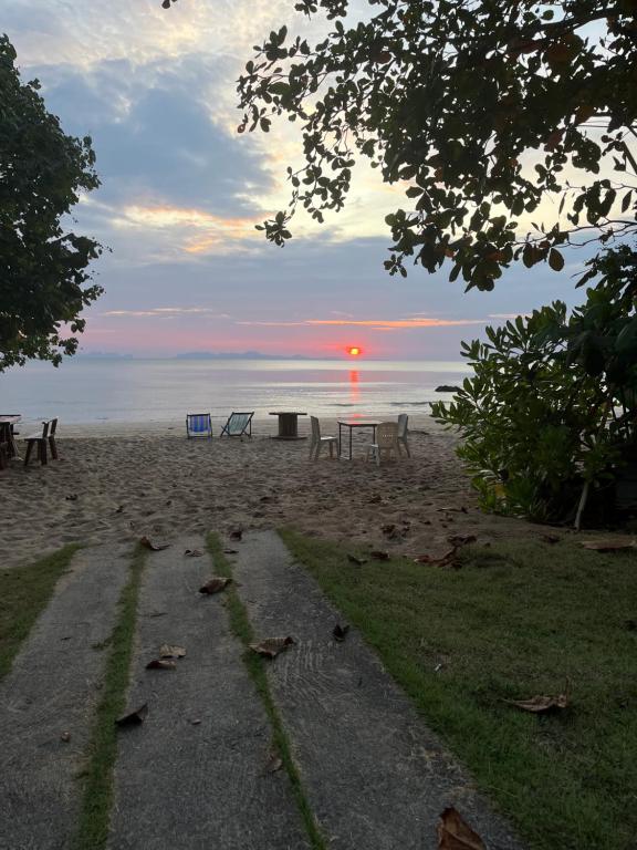 a sunset on the beach with a table and benches at Sun Smile Beach Koh Jum in Ko Jum