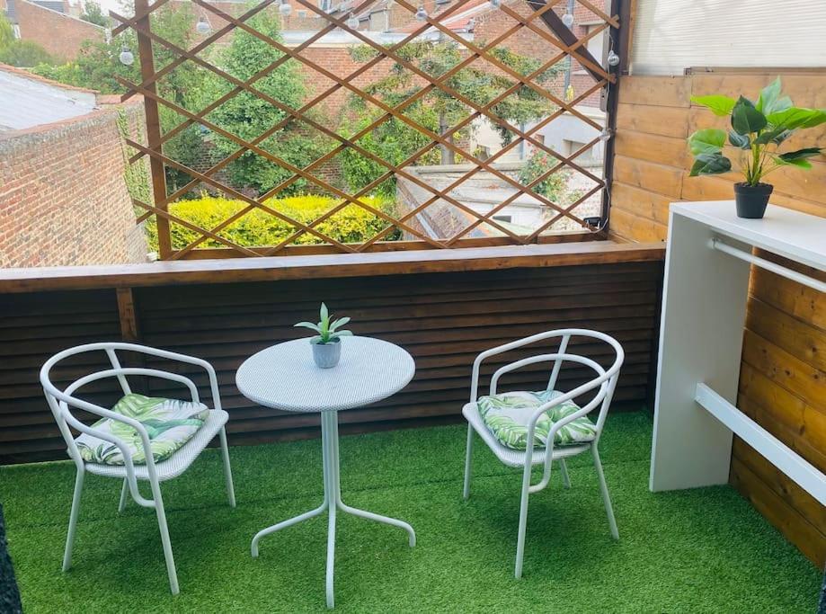 d'une terrasse avec une table, deux chaises et une fenêtre. dans l'établissement La Terrasse, charmant studio en Centre Ville, à Lens