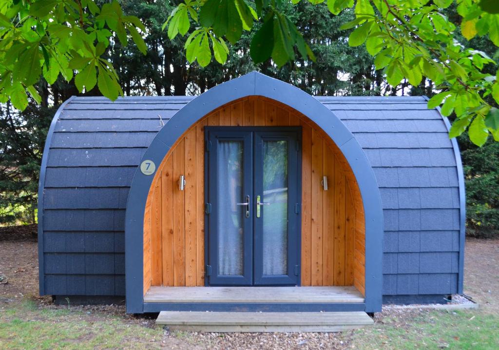 un pequeño cobertizo con una puerta de madera en el césped en Camping Pods Sand Le Mere, en Tunstall