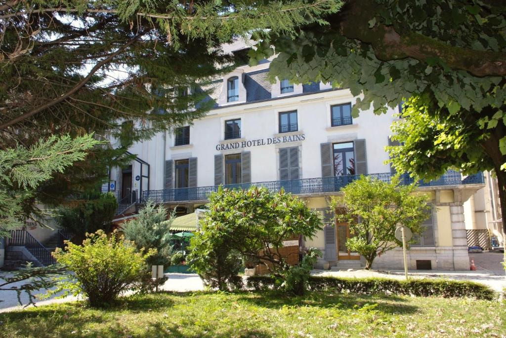 サラン・レ・バンにあるLogis Grand Hôtel Des Bainsの目の前に木々が植えられた白い大きな建物