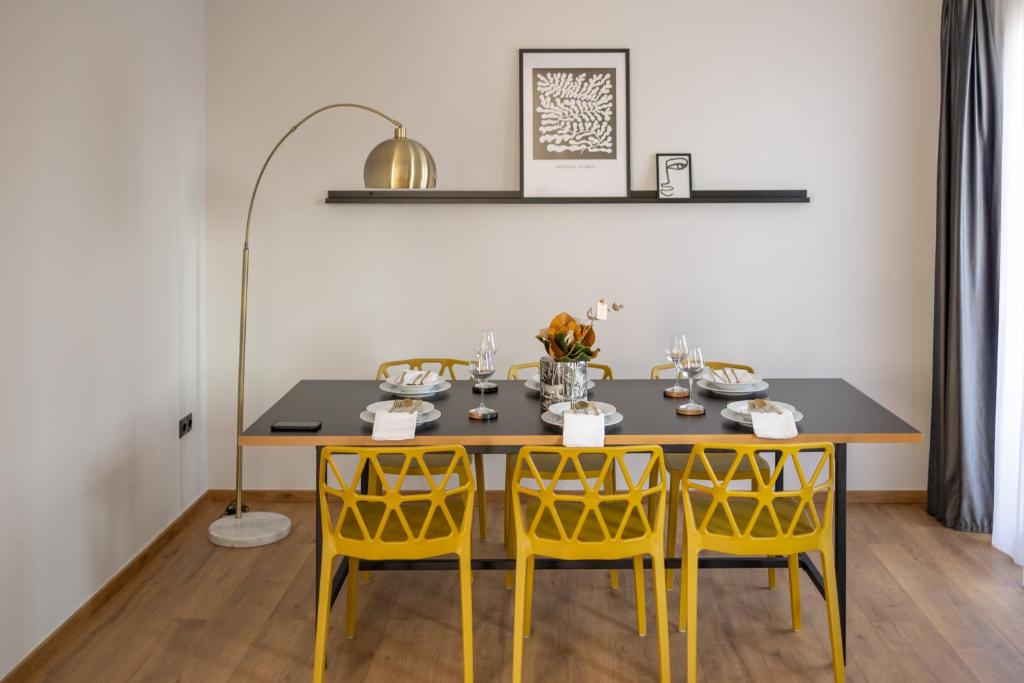 a dining room with a table and yellow chairs at Kaleo Chios Luxury Apartments in Chios