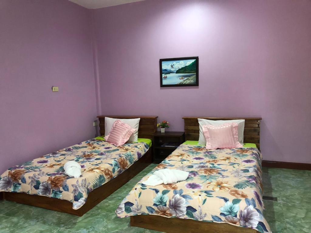 duas camas num quarto com paredes roxas em Green Happy Homestay em Phatthalung