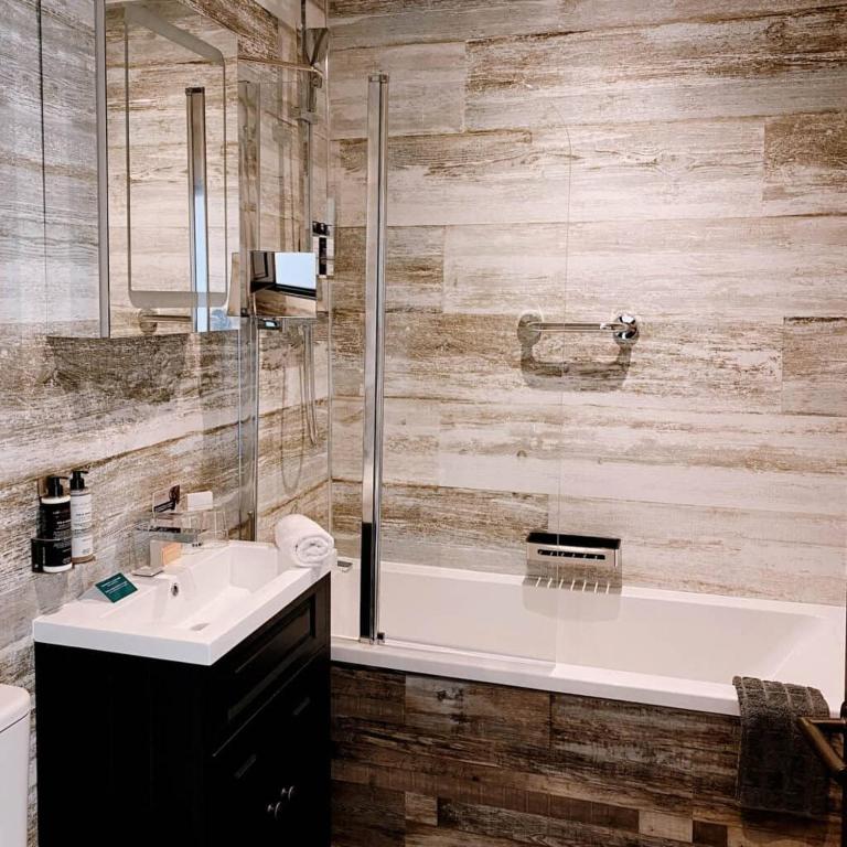 a bathroom with a tub and a sink and a shower at The Woolacombe Bay Hotel in Woolacombe