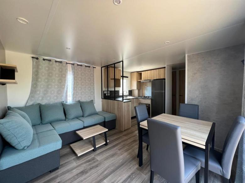 uma sala de estar com um sofá azul e uma mesa em Superbe Mobil home 6-8 personnes (57) em Saint-Jean-de-Monts