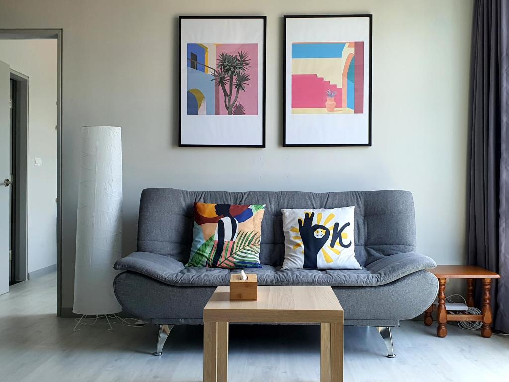 a living room with a blue couch and three paintings at Jesselton Quay by Bunga Raya Homes in Kota Kinabalu