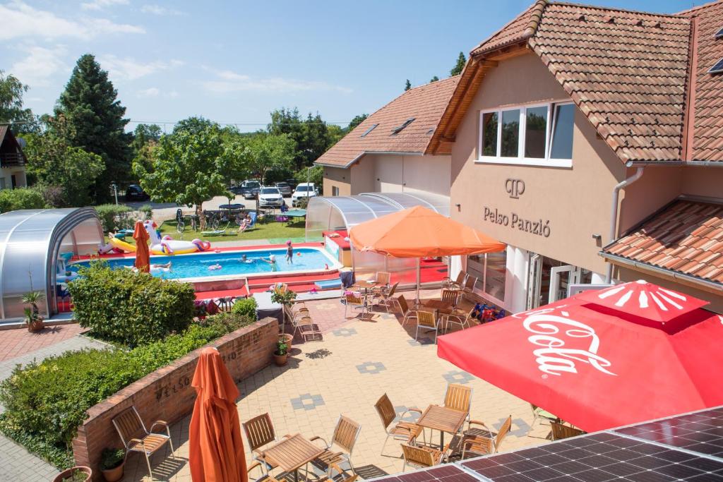 a pool with chairs and umbrellas next to a building at Pelso Panzio in Balatonmáriafürdő