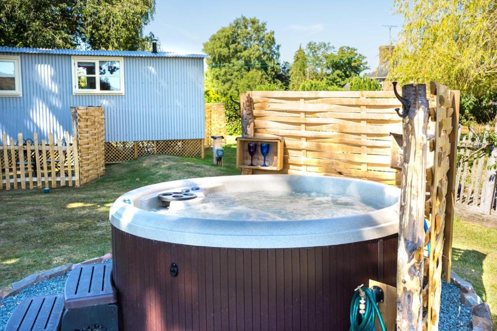 una bañera de hidromasaje en un patio con una valla de madera en The Hideaway Hut - 1 Bed Shepherds Hut - Hereford en Hereford