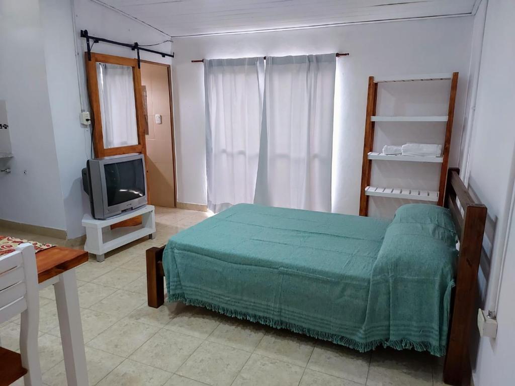 a bedroom with a green bed and a tv at Laprida2 in Curuzú Cuatiá