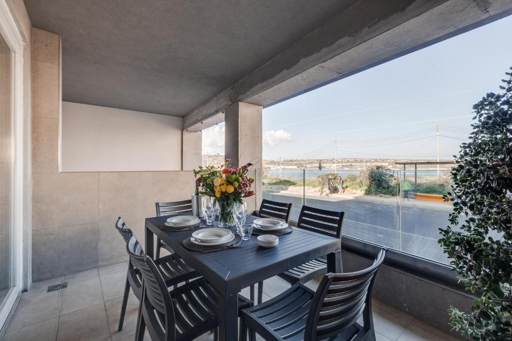 ein Esszimmer mit einem Tisch und Stühlen sowie einem großen Fenster in der Unterkunft 9ten11 Seafront in Mellieħa