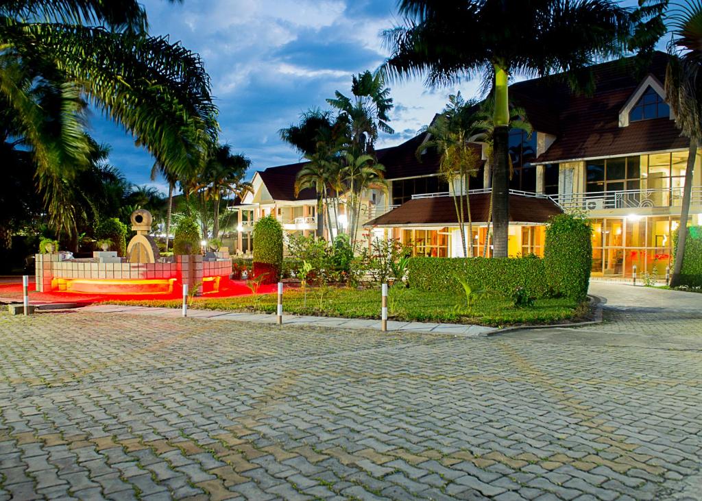 a house with palm trees in front of a brick driveway at Hotel Safari Gate in Bujumbura