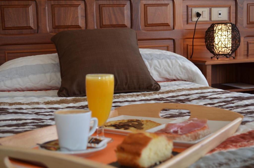 una bandeja de comida y un vaso de zumo de naranja en la cama en Hotel Celta Galaico, en Viveiro