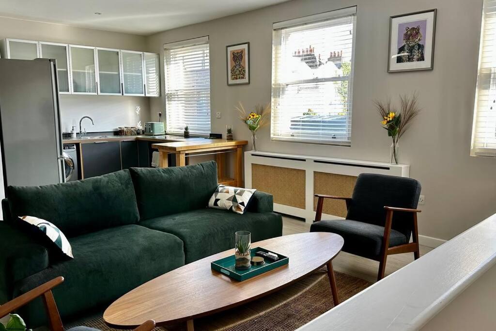 sala de estar con sofá verde y mesa en Sienna's 2 - bedroom apartment, London, N1., en Londres