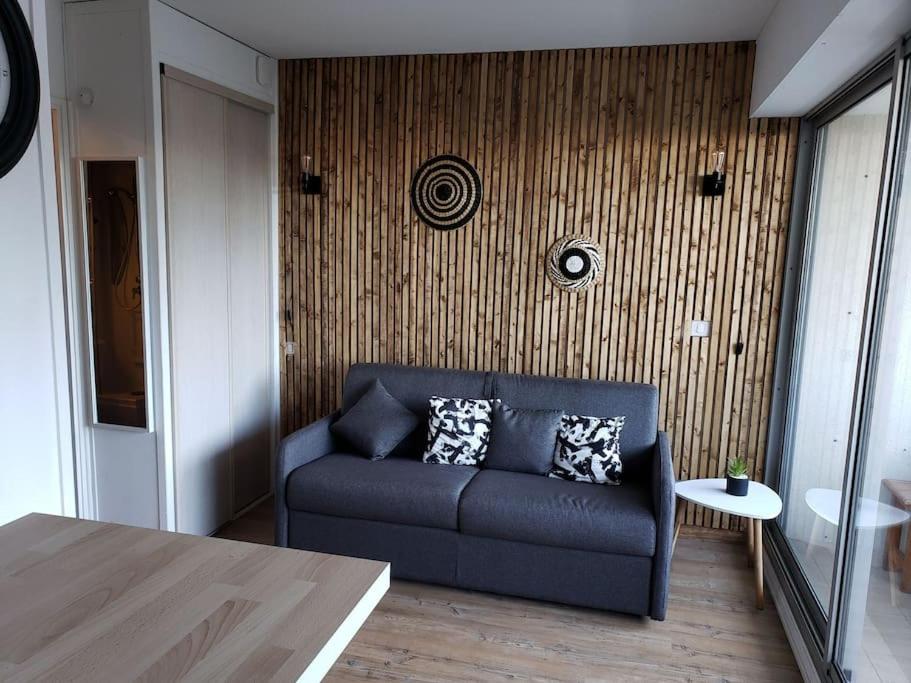 sala de estar con sofá azul frente a la pared en appartement résidence val soleil. en Eaux-Bonnes