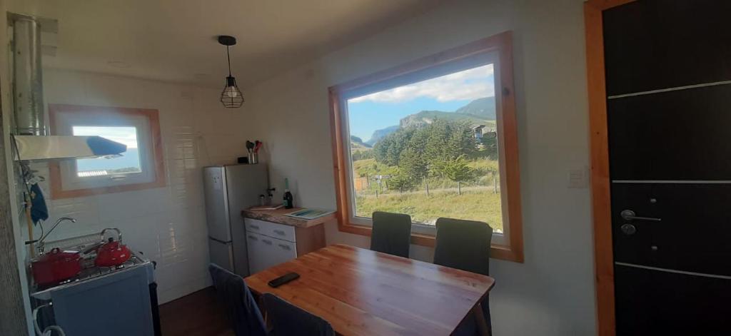 uma cozinha com uma mesa de madeira e uma janela em Cabañas Kápenken, #2 em Coihaique