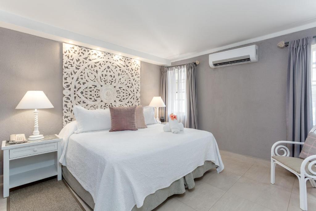 a bedroom with a white bed and a chair at Sugar Bay Barbados - All Inclusive in Bridgetown