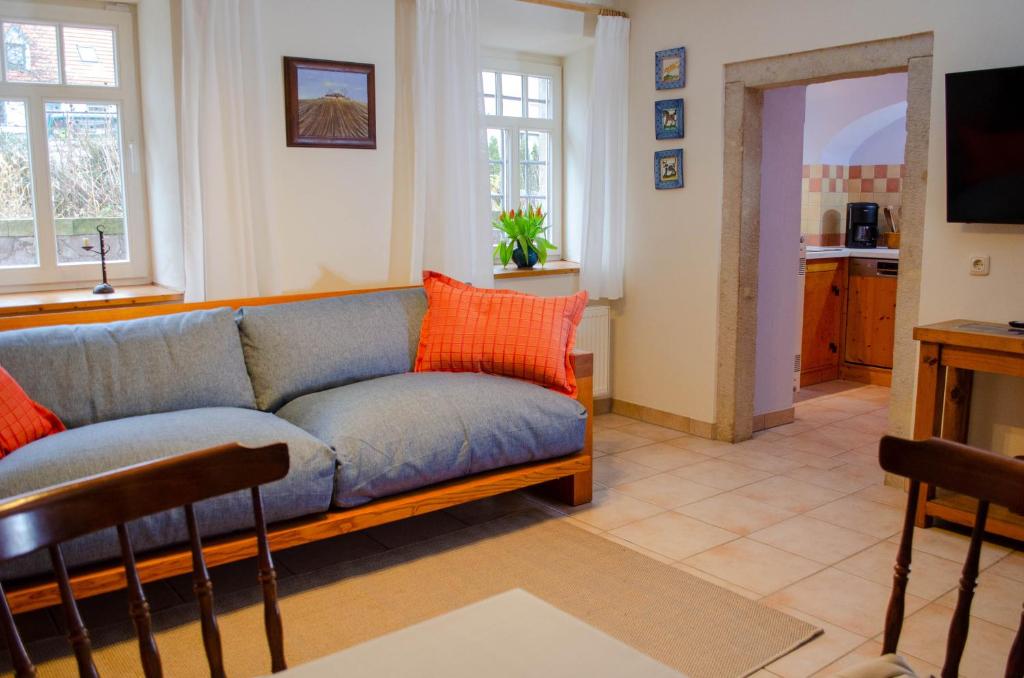 uma sala de estar com um sofá azul e almofadas laranja em Fährmannshof im Elbtal em Klipphausen