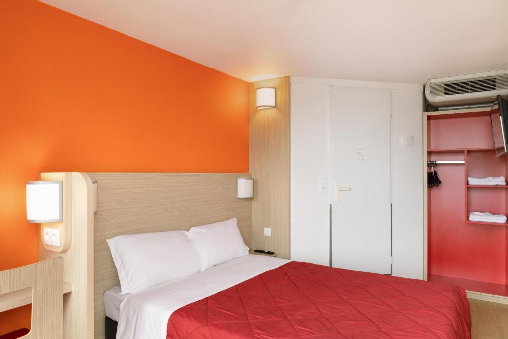 a bedroom with a bed with an orange wall at Premiere Classe Meaux Nanteuil Les Meaux in Nanteuil-lès-Meaux