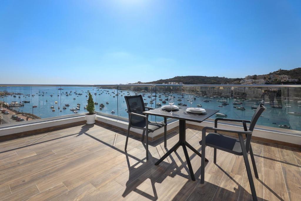 een tafel en stoelen op een balkon met uitzicht op een haven bij Seaview Stays in St Paul's Bay