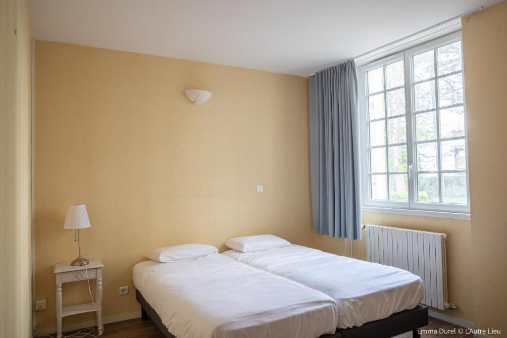 2 łóżka pojedyncze w pokoju z oknem w obiekcie L'Autre Lieu w mieście Cherbourg en Cotentin