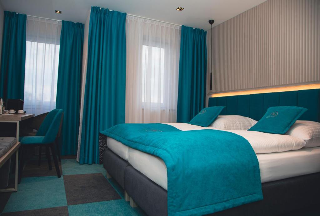 a bedroom with blue curtains and a large bed at Friends Hotel Kerpen in Kerpen