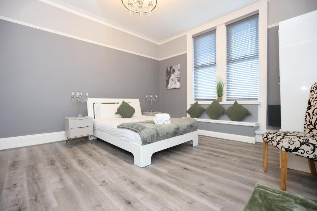 a white bedroom with a bed and two windows at Hotel Anfield in Liverpool