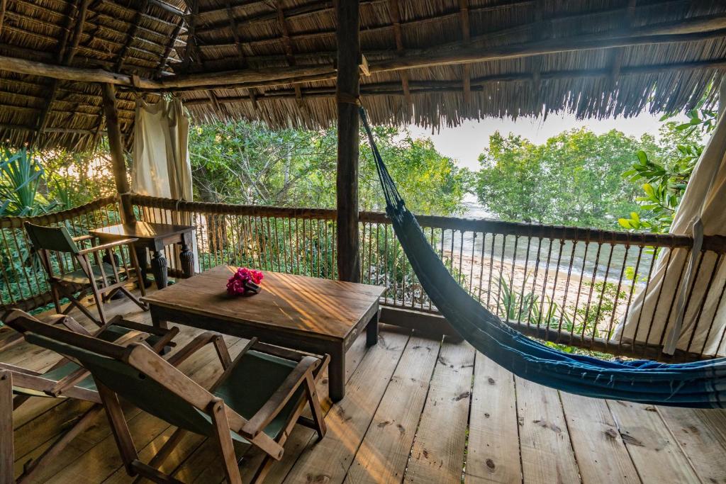 - une terrasse couverte avec un hamac, une table et des chaises dans l'établissement Kitu Kiblu, à Baleni