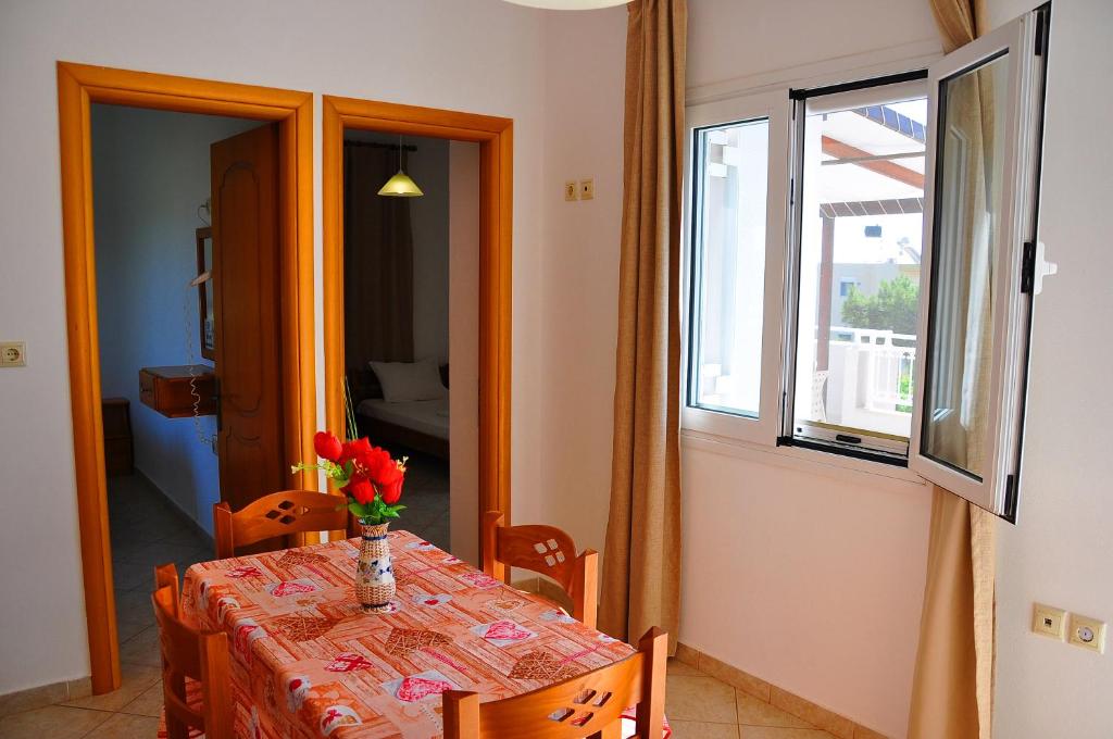 a dining room table with a vase of flowers on it at Lagos Studios & Apartments in Palekastron