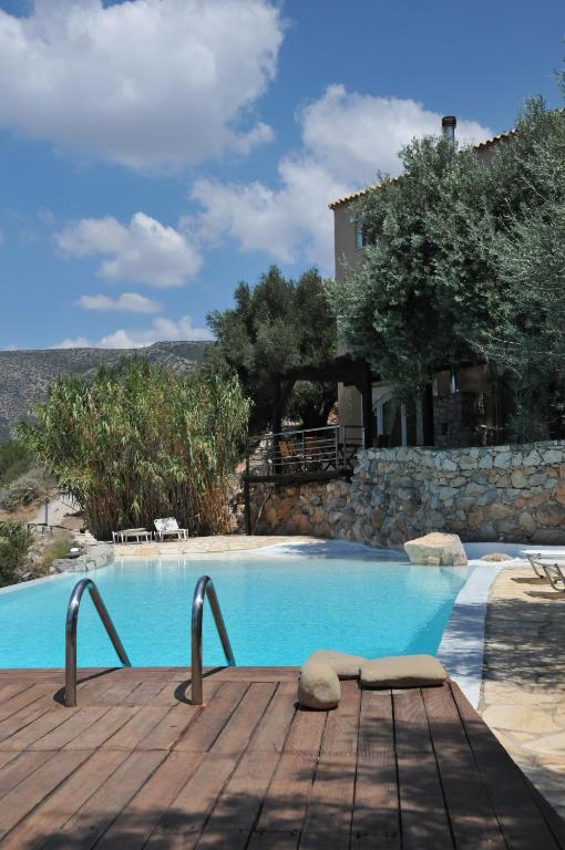 a pool with a wooden deck next to a house at Melolia Estate in Thiva