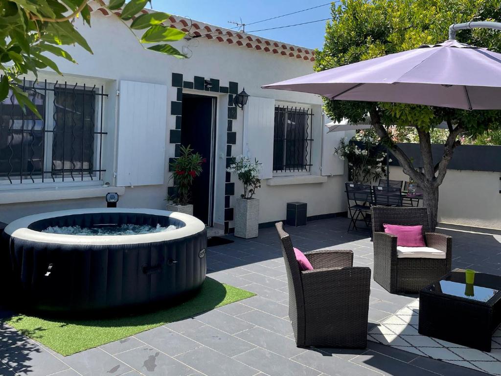 a patio with a hot tub and chairs and an umbrella at Key Largo villa 2p avec pkg clim grande terrasse avec jacuzzi proche port et plage in Bandol