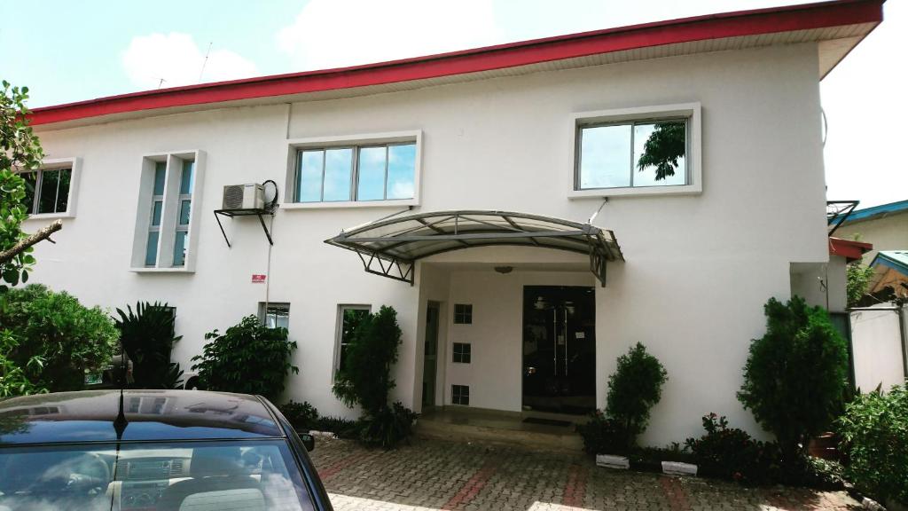 una casa blanca con un coche aparcado delante de ella en The Ambassadors Hotel en Lagos