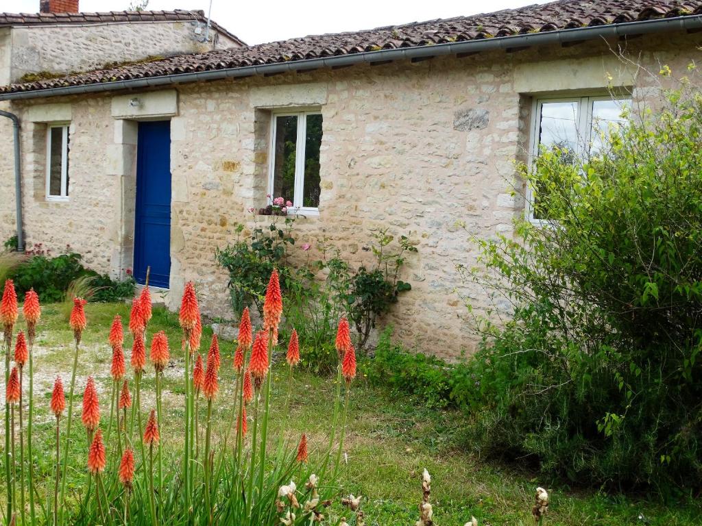 una casa con flores rojas delante de ella en Propriete d'une chambre avec jardin clos et wifi a La Mothe Saint Heray, en La Mothe-Saint-Héray