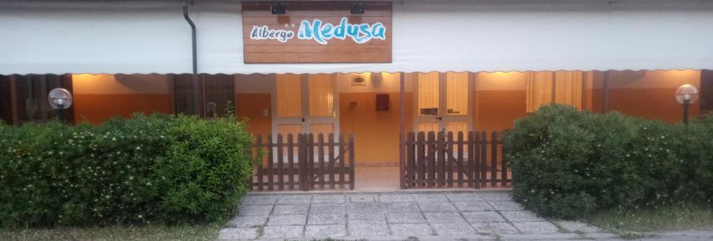 une porte d'entrée d'un bâtiment avec un panneau sur celui-ci dans l'établissement Albergo Medusa, à Punta Marina
