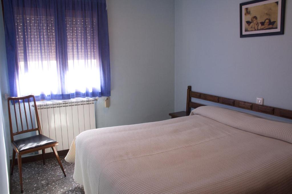 een slaapkamer met een bed, een stoel en een raam bij Hotel Casa Duaner in Guardiola de Berguedà