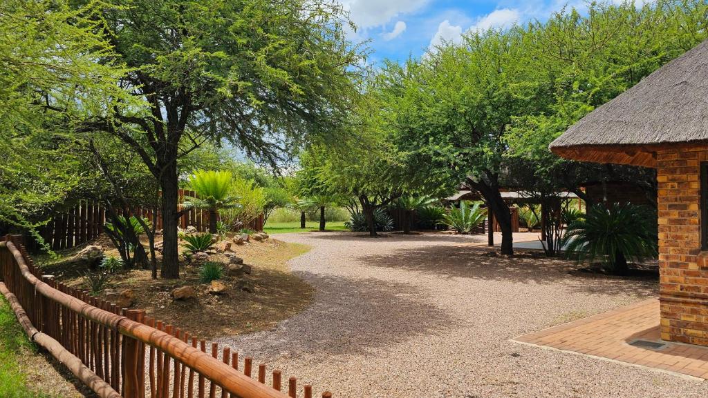 a garden with a fence and trees in the background at Makhato Bush Lodge 48 in Bela-Bela