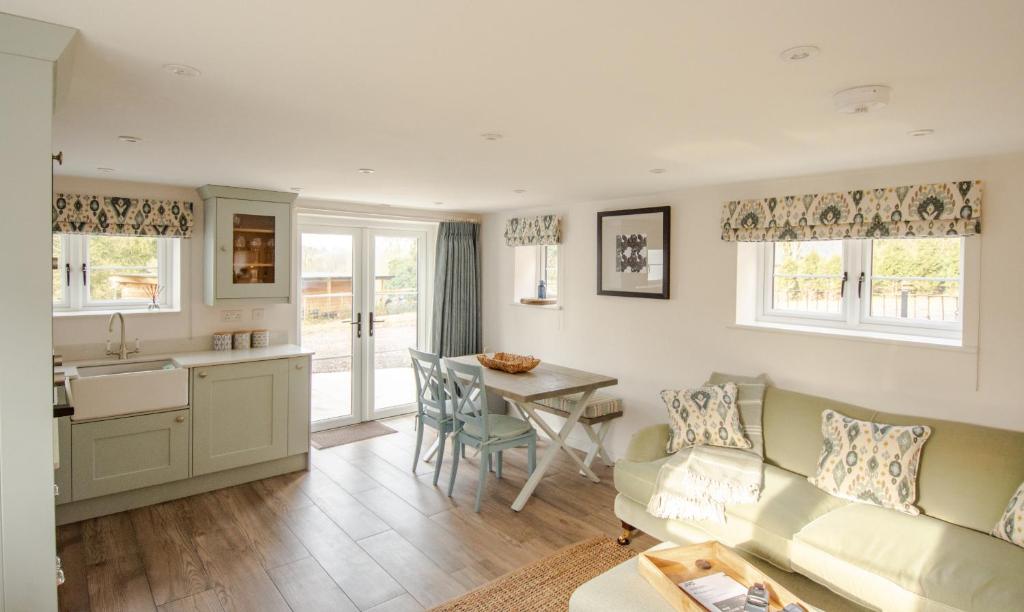 ein Wohnzimmer mit einem Sofa und einem Tisch in der Unterkunft Finwood Green Farm Holiday Cottages-The Calf Shed and The Milk Parlour in Henley in Arden