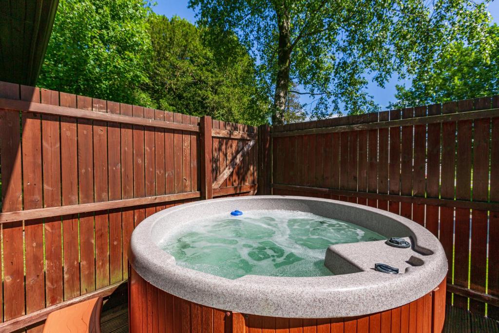 uma banheira de hidromassagem ao lado de uma cerca de madeira em Bluebell Lodge 2 with Hot Tub em Newton Stewart