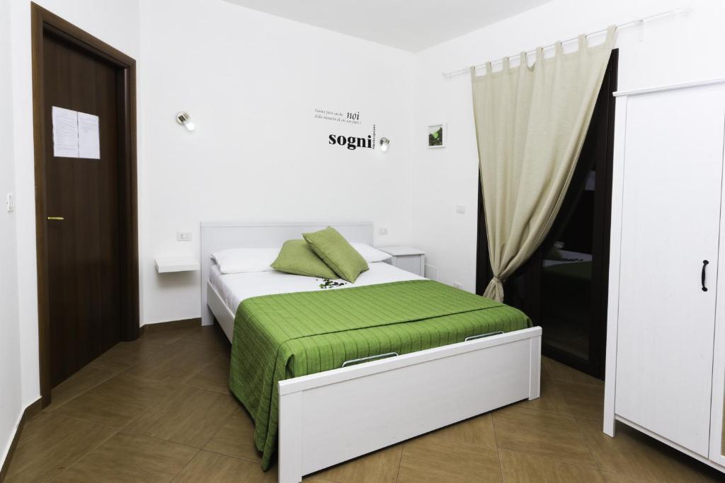 ein Schlafzimmer mit einem Bett mit einer grünen Decke in der Unterkunft Dolce Salento in Villaggio Resta