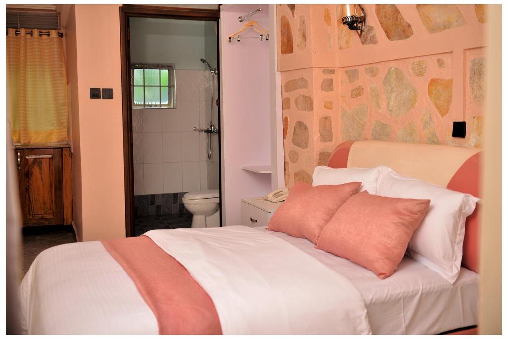 a bedroom with a white bed with a pink pillow at Ruby Haven in Kampala