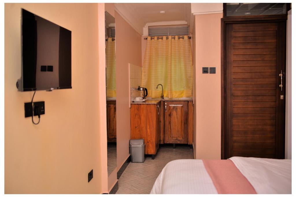 a room with a bed and a tv and a kitchen at Ruby Haven in Kampala