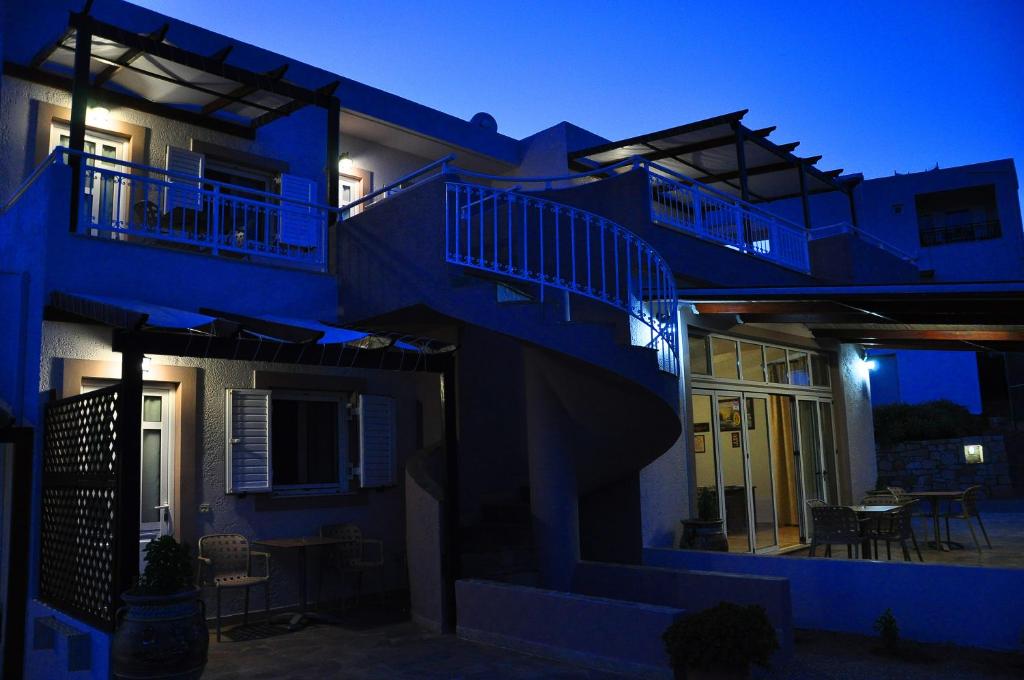 a blue building with stairs and a patio at night at Lagos Studios & Apartments in Palekastron