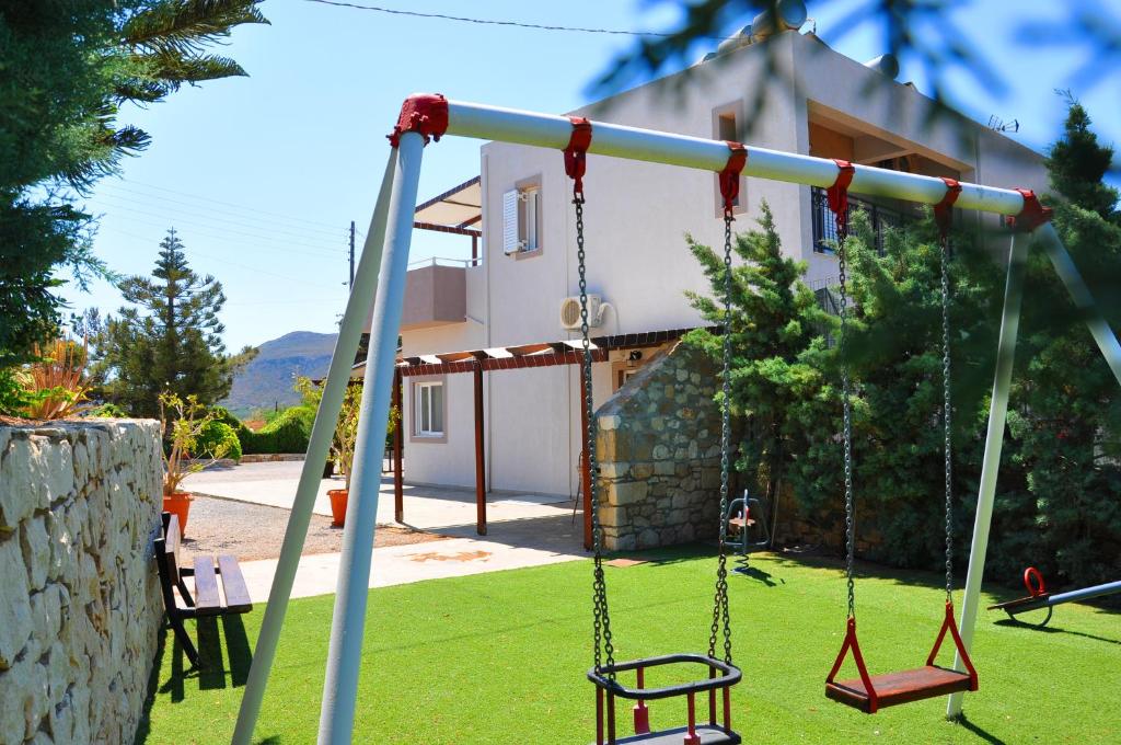 a swing set in a yard with a house at Lagos Studios & Apartments in Palekastron
