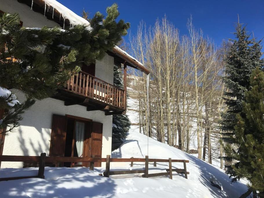 a log cabin in the snow with a wooden porch at Cozy mountains apartments in Borgata Sestriere