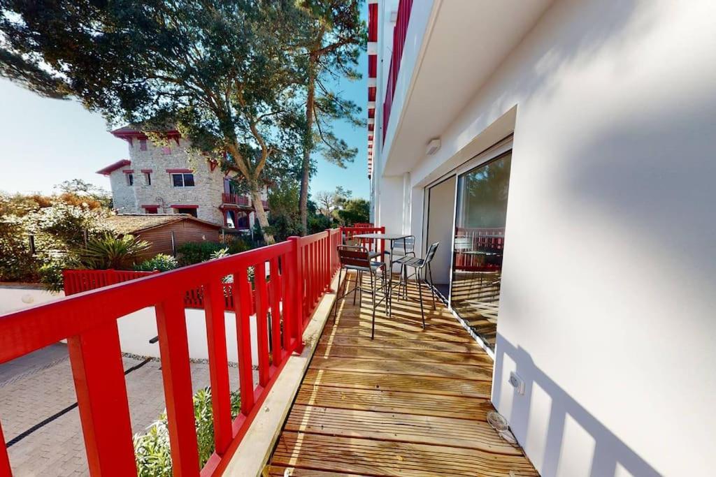 a wooden walkway leading to a balcony with a red fence at Haut Saint Georges - Un emplacement exceptionnel au centre-ville et au calme à quelques pas du lac marin in Soorts-Hossegor