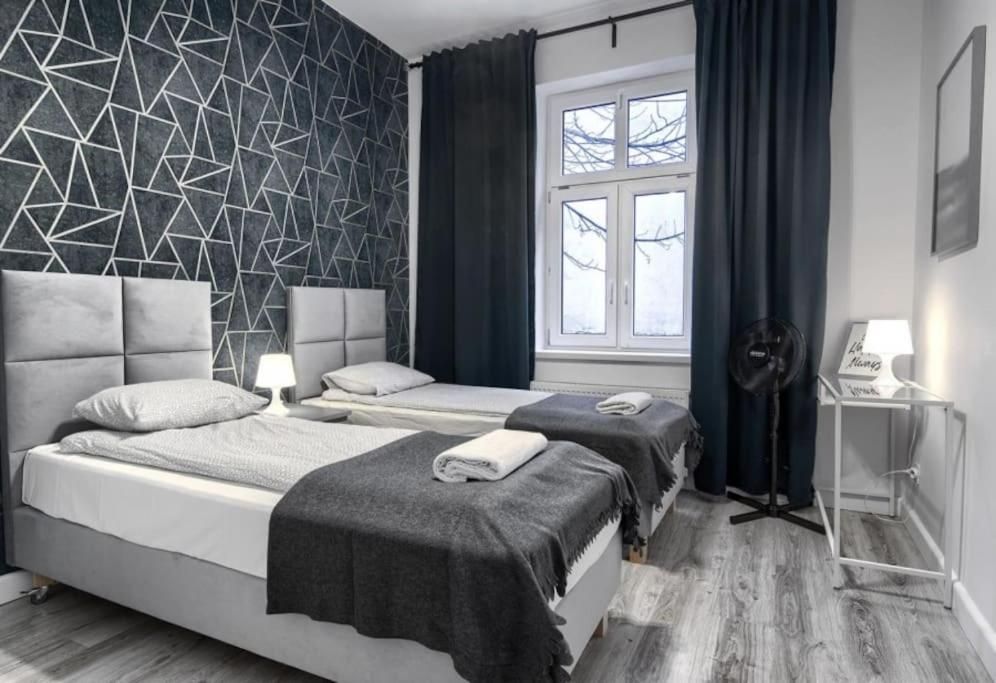 een slaapkamer met 2 bedden en een geometrische muur bij MonteFerber Modern Stylish Apartment in Center of Sopot in Sopot